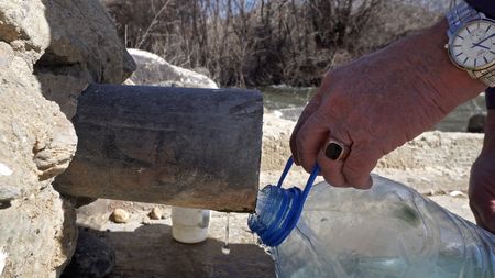 Old man fill plastic bottle with thermal drink water from natural springの写真素材