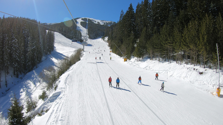 Aerial view of skiers and snowboarders on ski slope on sunny dayの写真素材