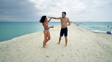 Young couple having fun fighting on the beachの写真素材