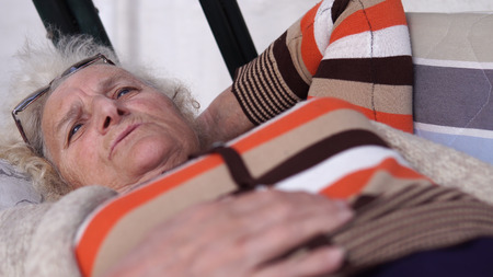 Talking elder woman lying in the garden porch swing bed, closeupの写真素材