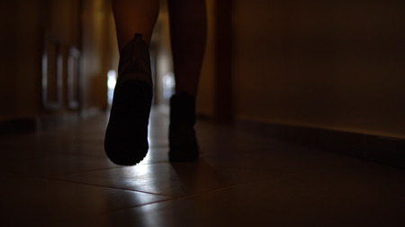 Dolly with low-section legs of silhouette woman running along corridor hallway in slow motionの写真素材