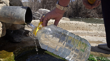Old man fill plastic bottle with thermal drink water from natural springの写真素材