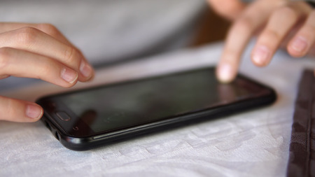 leisure, children, technology, internet communication and people concept - Closeup of boy with smartphone texting message or playing game on tableの写真素材