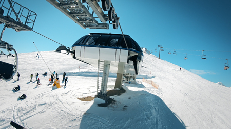 Ski lift with seats going over the mountain with view of people ski and snowboard on slopeの写真素材