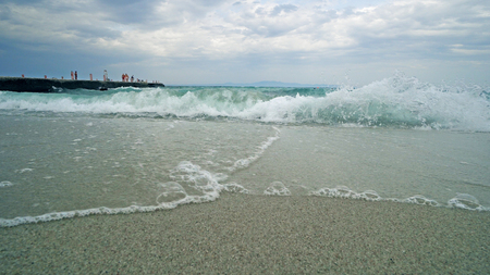 Splashing storm waves on a beach near pier.の写真素材