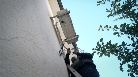 Repairman Works On Air Conditioner outdoor unit, cinematic shotの写真素材
