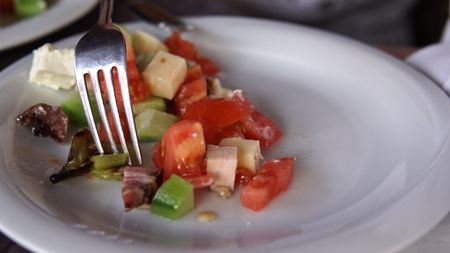 Eating a fresh mixed salad with tomato, cheese, ham, mushrooms, cinematic dof close upの写真素材