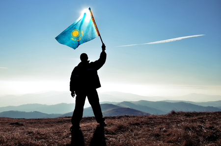 Successful silhouette man winner waving Kazakhstan flag on top of the mountain peakの写真素材