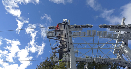 Bottom view of the pylon on the ski lift in wintertime against the blue sky, bottom view of skis of skiers riding the ski liftの写真素材