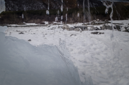 outdoor view of ice blocks at frozen water in winter texture with light white snow covering chunks...