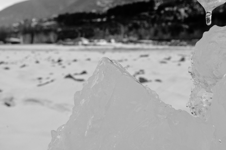 outdoor view of ice blocks at frozen water in winter texture with light white snow covering chunks of cracked ice on a frozen winter groundの写真素材