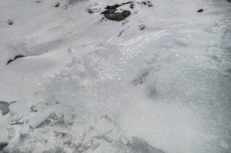 outdoor view of ice blocks at frozen water in winter texture with light white snow covering chunks of cracked ice on a frozen winter groundの写真素材