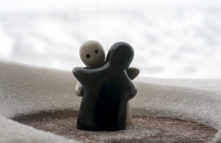 Love melts the ice Valentine `s day concept. F girl and a boy dolls hugs each other, standing on the white snow with blurred background. Hugging sculptures. Souvenir. Marble object. Love. Sympathyの写真素材