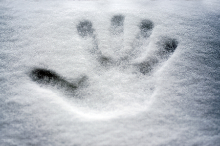 Perfect hand print in fresh snow, with blurred background of lake and mountainの写真素材