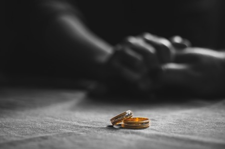 Love, Valentine`s day and wedding concept. Two wedding rings with man and woman hands blurred in the background. Selective focusの写真素材