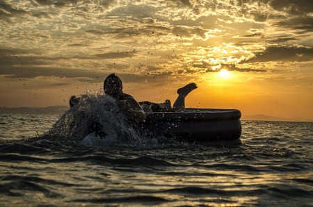 Silhouette of a man on an inflatable mattress swimming in the water of Caspian Sea at sunset time. Summertime in Azerbaijan, Absheron, Bakuの写真素材