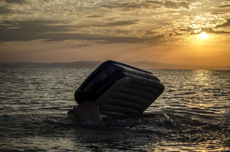 Silhouette of a man on an inflatable mattress swimming in the water of Caspian Sea at sunset time. Summertime in Azerbaijan, Absheron, Bakuの写真素材