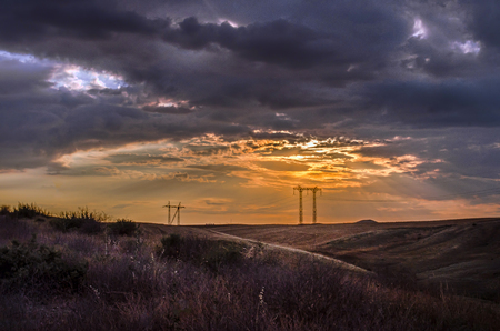 Road vanishing to the horizon under sun rays coming down trough the dramatic stormy clouds. Sunset at the mountain road. Azerbaijan,の写真素材