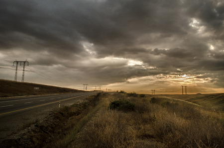 Road vanishing to the horizon under sun rays coming down trough the dramatic stormy clouds. Sunset at the mountain road. Azerbaijan,の写真素材
