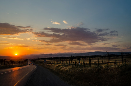 Road vanishing to the horizon under sun rays coming down trough the dramatic stormy clouds. Sunset at the mountain road. Azerbaijan,の写真素材