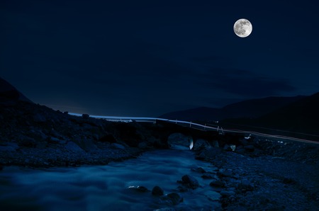 mountain river with stones and grass in the forest at the foot of mountain slope at night in moon light. Azerbaijan natureの写真素材