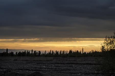Road vanishing to the horizon under sun rays coming down trough the dramatic stormy clouds. Sunset at the mountain road. Azerbaijan,の写真素材