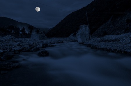 mountain river with stones and grass in the forest at the foot of mountain slope at night in moon light. Azerbaijan natureの写真素材