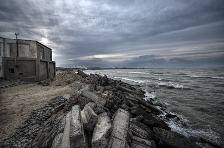 Beautiful surreal landscape of abandoned house and ladder on rocky seashore at sunset time. Cloudy weather. Caspian Sea, Azerbaijan, Novkhaniの写真素材
