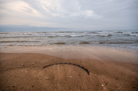 Sunset at the sea shore of a beach with rocks and stormy waves, beautiful seascape at Caspian sea Absheron, Azerbaijanの写真素材