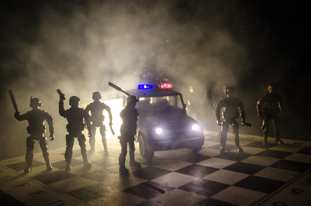 Anti-riot police give signal to be ready. Government power concept. Police on chessboard. Smoke on a dark background with lights. Blue red flashing sirens. Dictatorship powerの写真素材