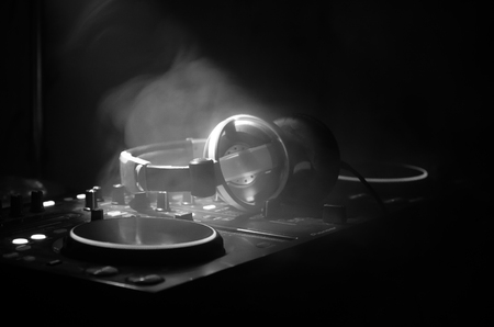 DJ Spinning, Mixing, and Scratching in a Night Club, Hands of dj tweak various track controls on dj's deck, strobe lights and fog, selective focus, close up. Dj Music club life conceptの写真素材