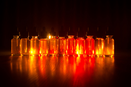 Vape concept. Smoke clouds and vape liquid bottles on dark background. Light effects. Useful as background or vape advertisement or vape background.の写真素材