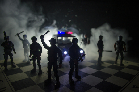 Anti-riot police give signal to be ready. Government power concept. Police on chessboard. Smoke on a dark background with lights. Blue red flashing sirens. Dictatorship powerの写真素材