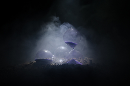 Time concept. Silhouette of Hourglass clock and smoke on dark background with hot yellow orange...