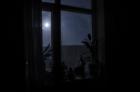 Night scene of moon seen through the window from dark room. Moonlight inside dark roomの写真素材