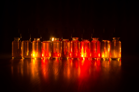 Vape concept. Smoke clouds and vape liquid bottles on dark background. Light effects. Useful as background or vape advertisement or vape background.の写真素材