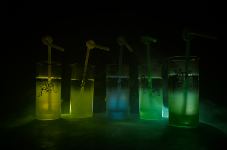 Five cocktails on the bar with smoke on dark background. Yellow, green and blue colored glasses. Club drinksの写真素材