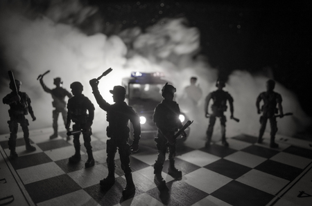Anti-riot police give signal to be ready. Government power concept. Police on chessboard. Smoke on a dark background with lights. Blue red flashing sirens. Dictatorship powerの写真素材
