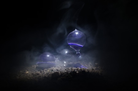 Time concept. Silhouette of Hourglass clock and smoke on dark background with hot yellow orange lighting, or symbols of time with copy space, sandglass or sand clock on chessboardの写真素材