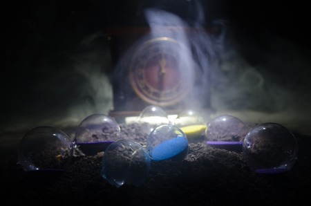 Time concept. Silhouette of Hourglass clock and smoke on dark background with hot yellow orange lighting, or symbols of time with copy space, sandglass or sand clock on chessboardの写真素材