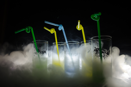 Five cocktails on the bar with smoke on dark background. Yellow, green and blue colored glasses. Club drinksの写真素材