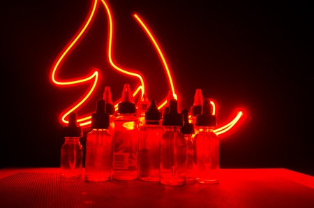 Vape concept. Smoke clouds and vape liquid bottles on dark background. Light effects. Useful as background or vape advertisement or vape background.の写真素材