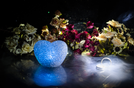 Wedding card, Wedding rings. Wedding bouquet, background. Flowering branch with white delicate flowers on wooden surface. Declaration of love, spring. Dark background with smoke and heart. Love coneptの写真素材