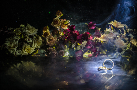 Wedding card, Wedding rings. Wedding bouquet, background. Flowering branch with white delicate flowers on wooden surface. Declaration of love, spring. Dark background with smoke and heart. Love coneptの写真素材