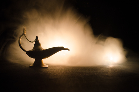 Antique Aladdin arabian nights genie style oil lamp with soft light white smoke, Dark background. Lamp of wishes conceptの写真素材