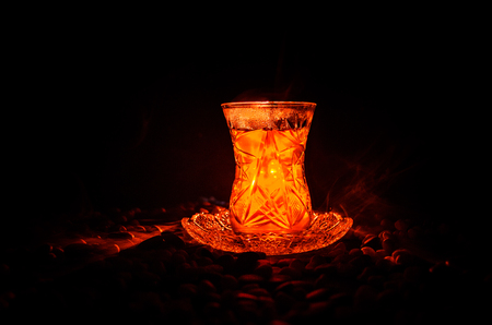 Turkish Azerbaijan tea in traditional glasse and pot on black background with lights and smoke. Eastern tea concept. Armudu traditional cupの写真素材