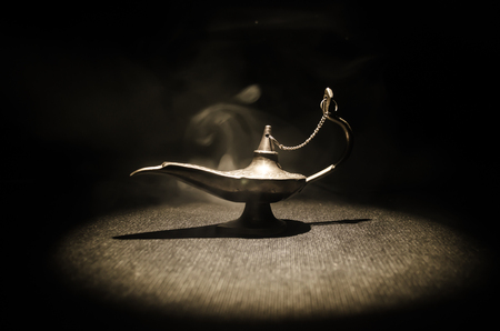Antique Aladdin arabian nights genie style oil lamp with soft light white smoke, Dark background. Lamp of wishes conceptの写真素材