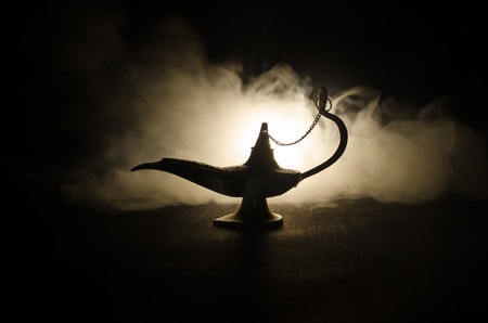 Antique Aladdin arabian nights genie style oil lamp with soft light white smoke, Dark background. Lamp of wishes conceptの写真素材