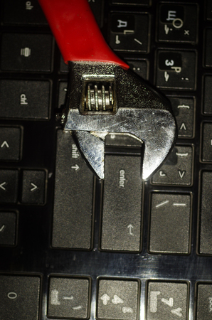 Wrench tool over a laptop on a dark background close up selective focus, repair service concept.の写真素材