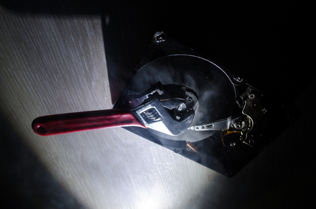 Adjustable wrench turn off a hard disk. On a dark background. Computer repair concept. Useful as...